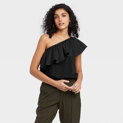 A model wears a black one-shoulder ruffle top with olive green pants
