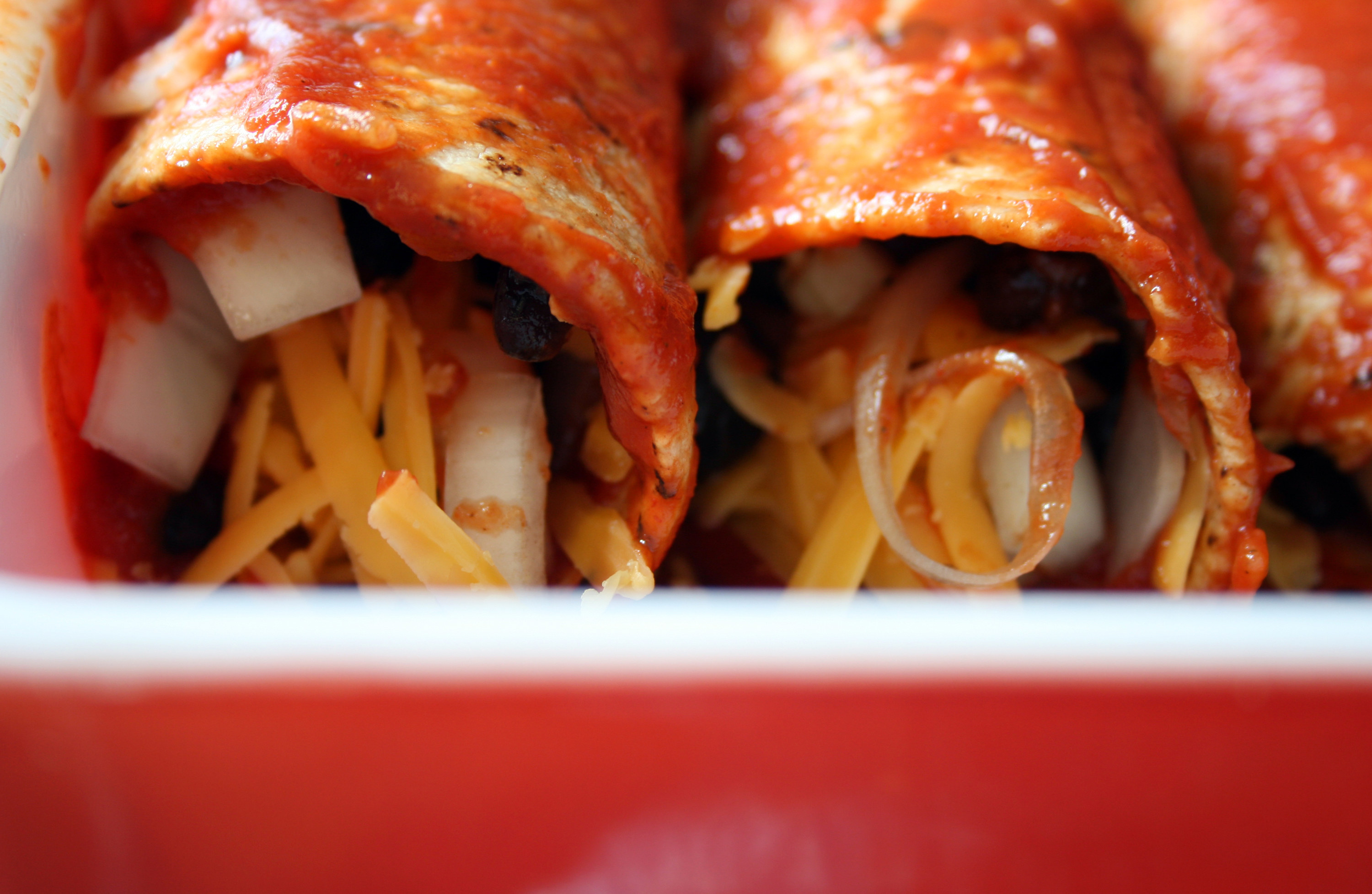 Close up shot of black bean, onion, and cheese enchiladas