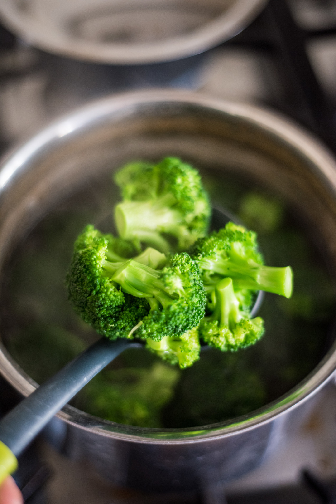 Straining boiled broccoli with a skimmer spoon