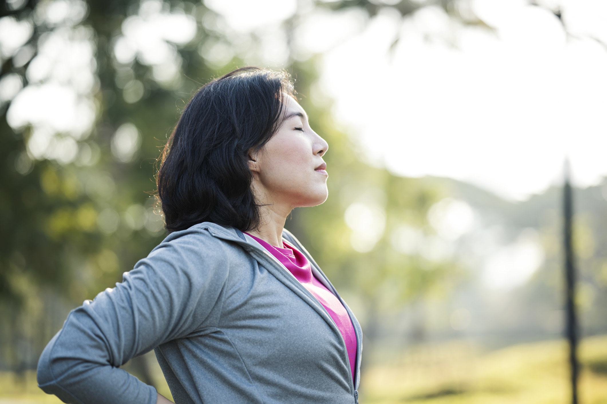 A woman with her eyes closed and clutching her back