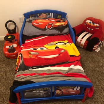 reviewer's photo of the car themed bed in their child's room