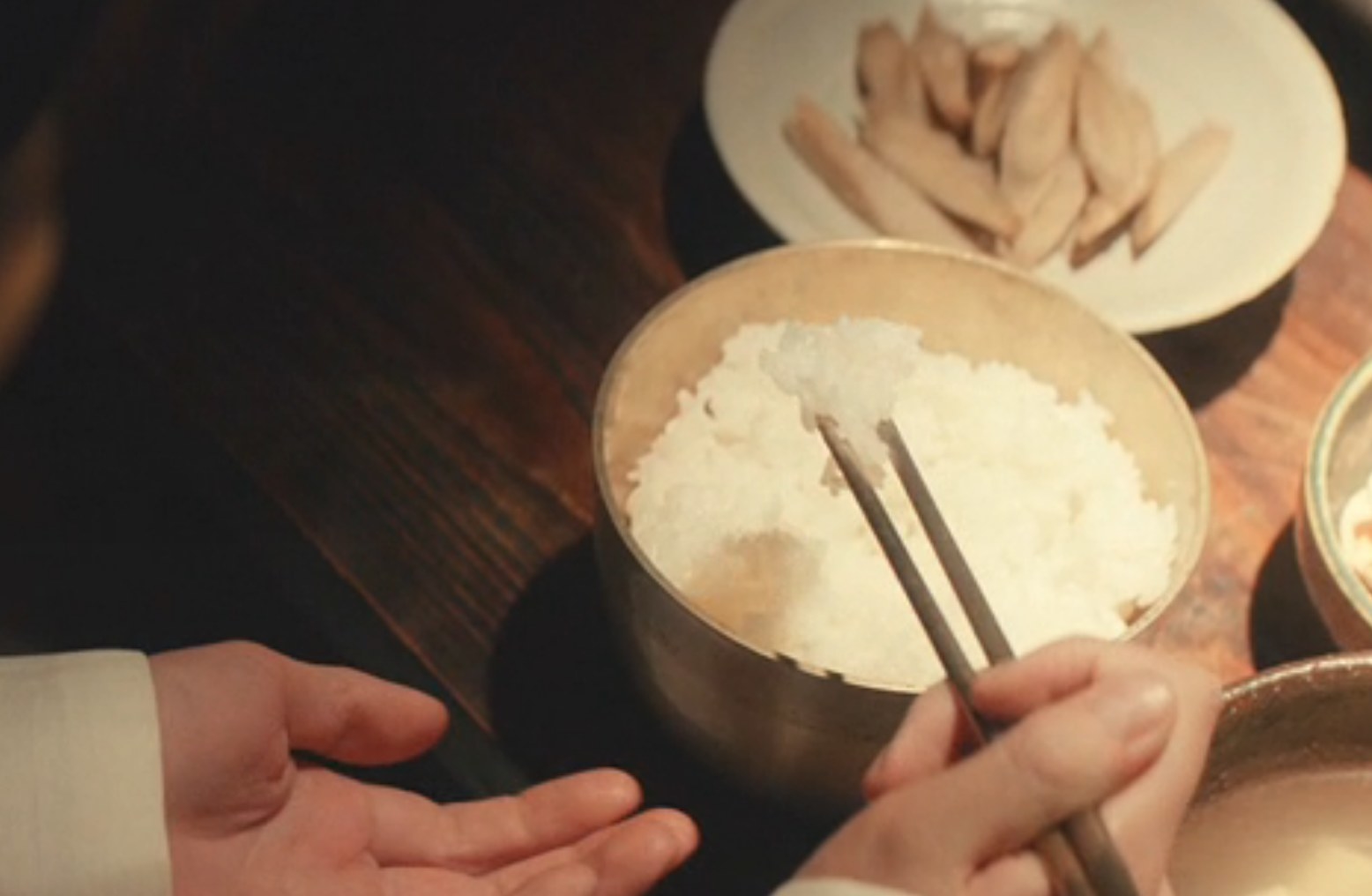 Sunja eating the precious rice her mother bought