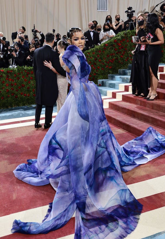 Teyana Taylor standing on the re carpet in a flowy tie-dyed gown