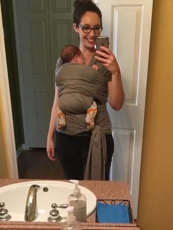 reviewer's photo carrying their baby in the grey wrap