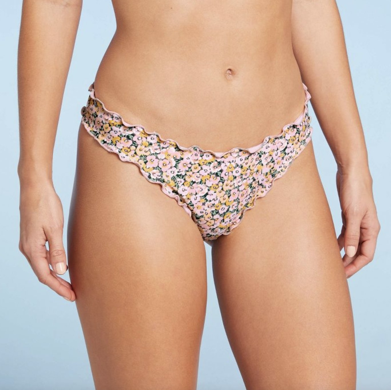 A person wearing a floral bikini bottom with ruffle trim