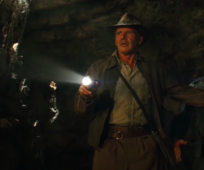 Harrison as Indiana Jones holding a flashlight