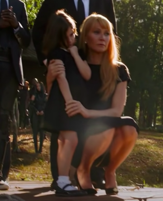 Gwyneth kneeling, looking sad, and holding on to a child