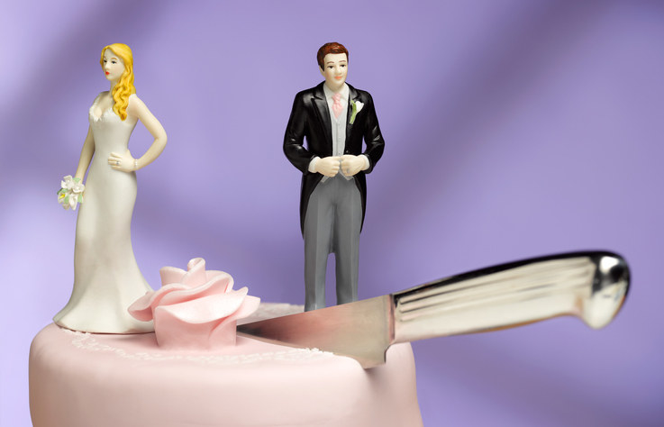 close up of a wedding cake with a knife in between the plastic bride and groom toppers