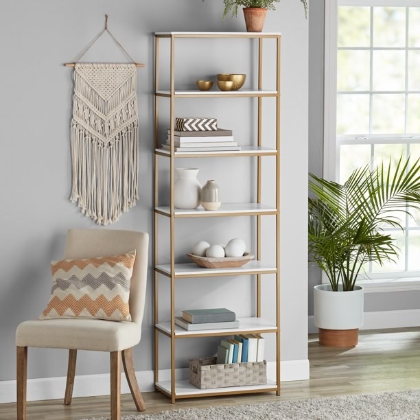 the gold bookcase with white shelving