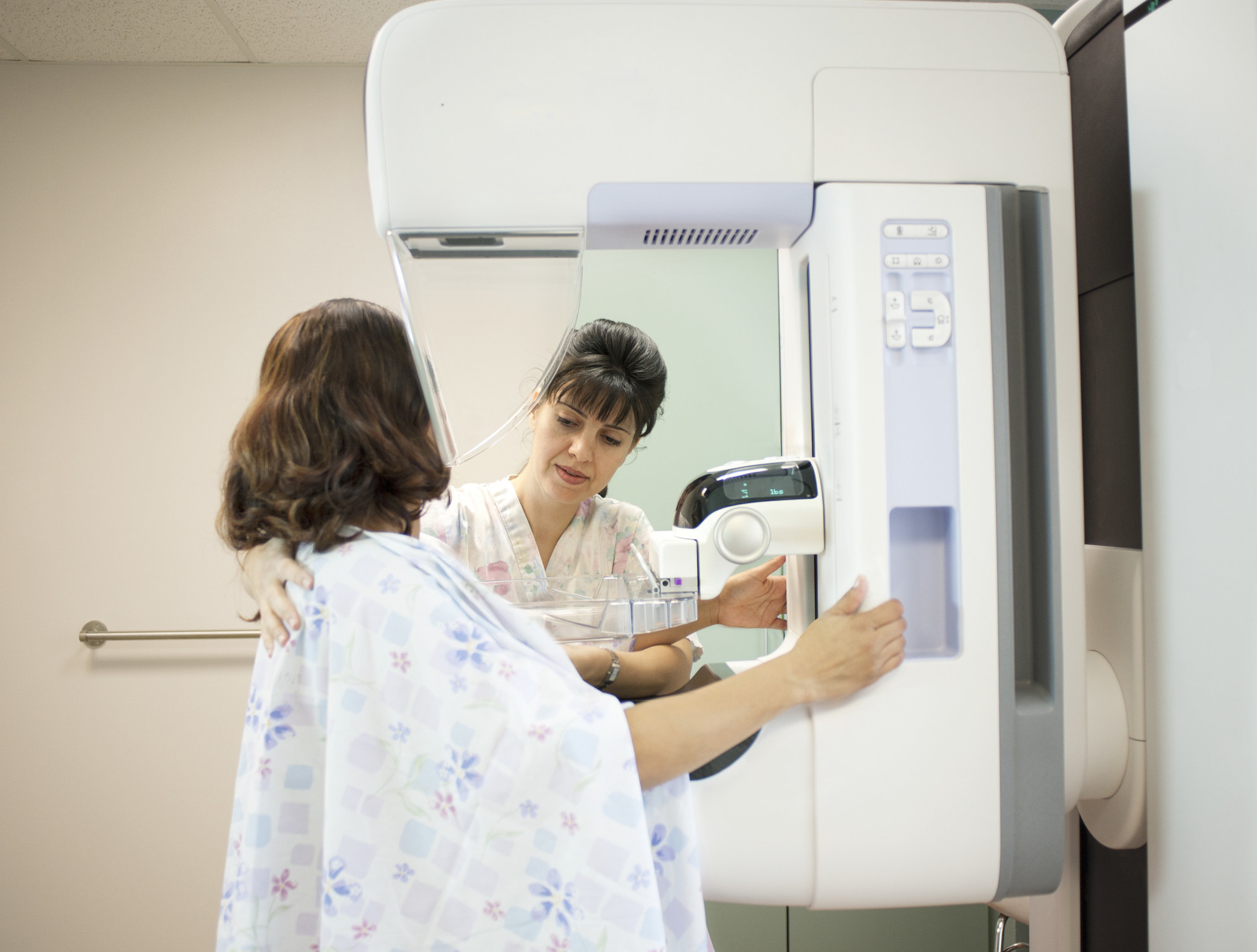 A woman has a mammogram done as a doctor stands near her