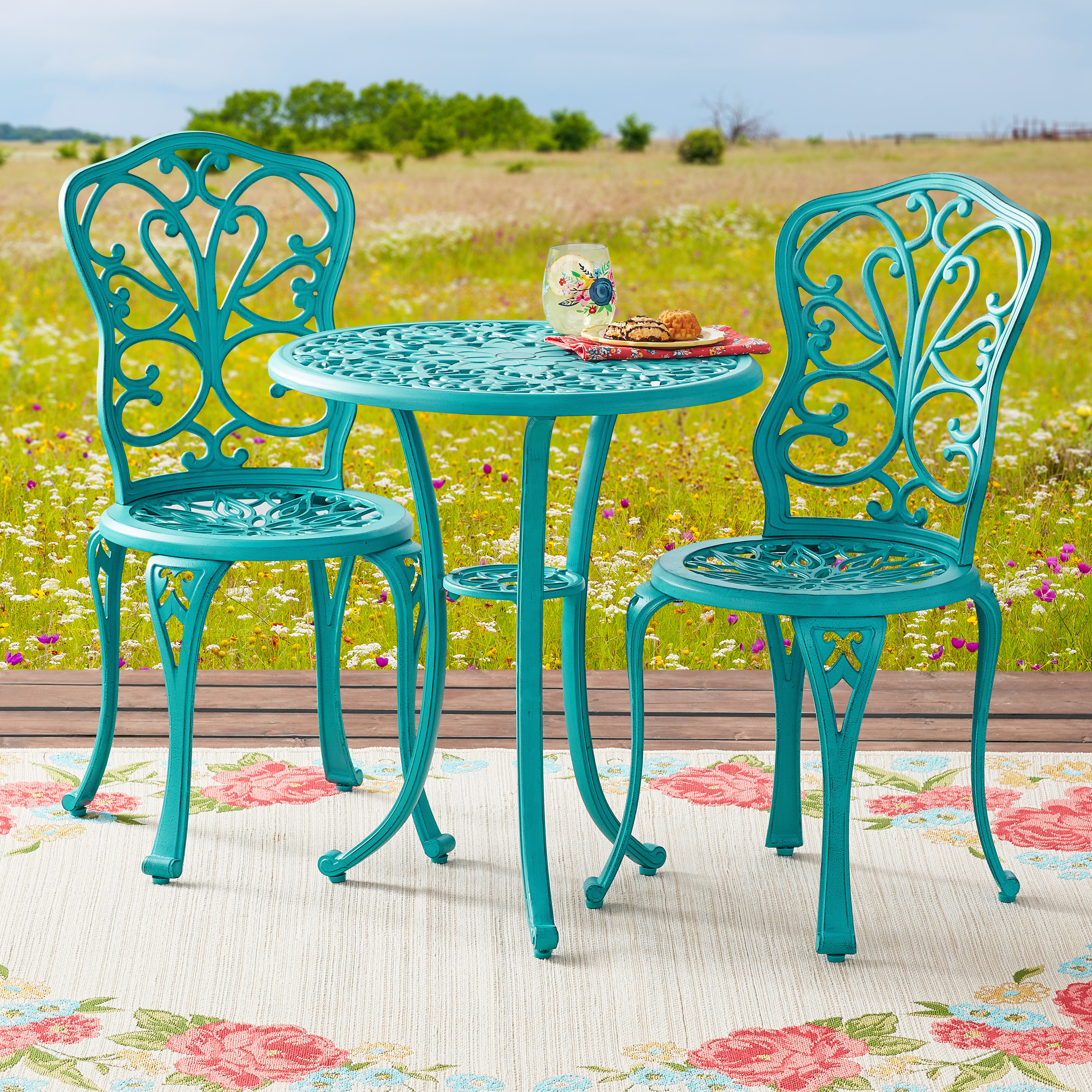 teal ornate cast iron small round table and two chairs