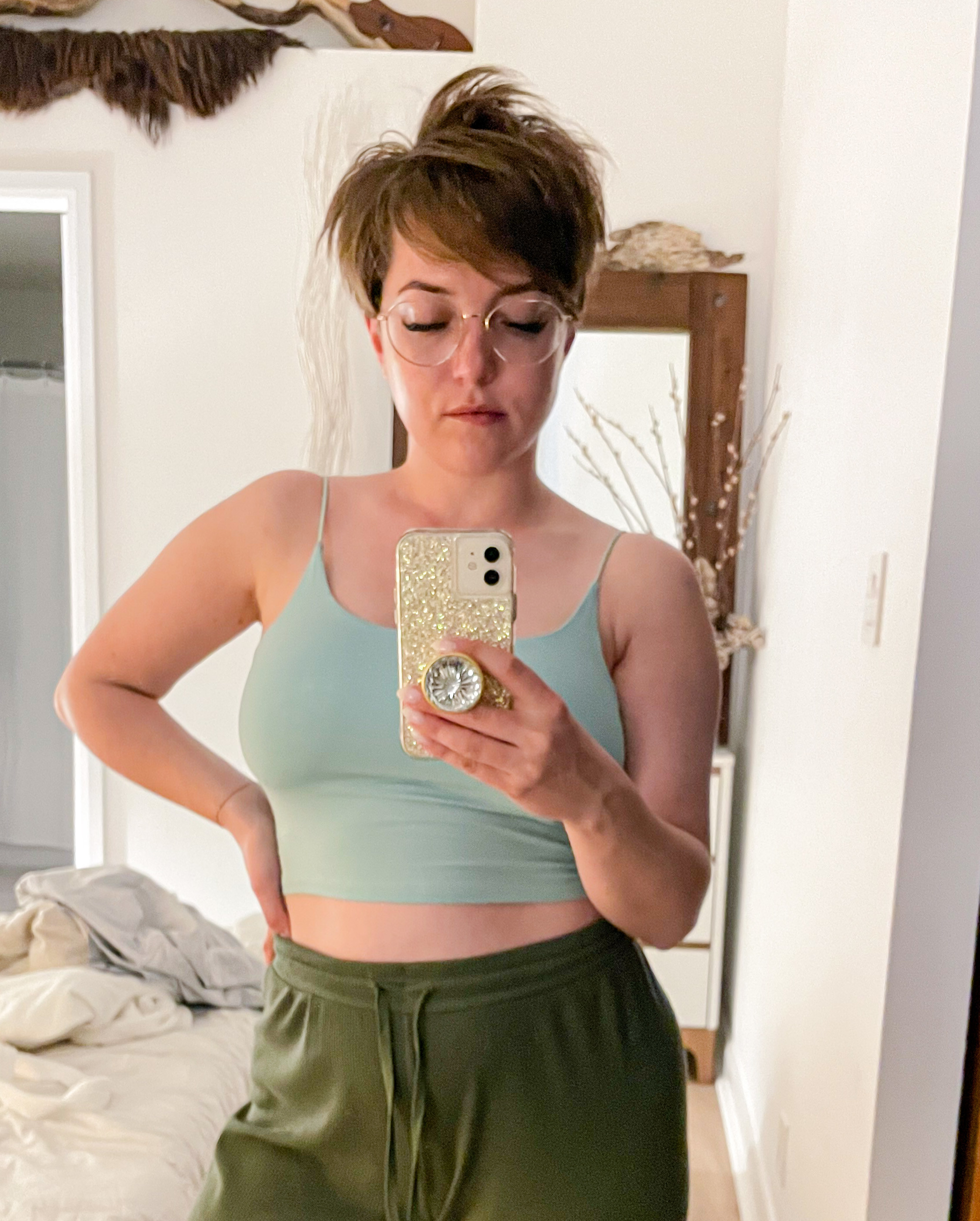 Victoria taking a mirror selfie while wearing one of the cropped tank tops