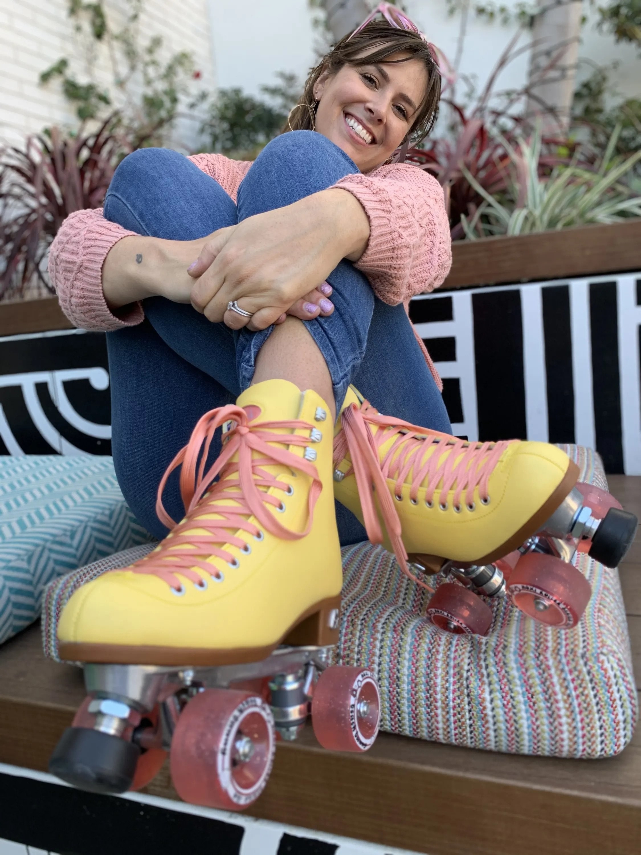 close-up of model&#x27;s light pink suede ankle-boot skates with hot pink laces, wheels, and brakes
