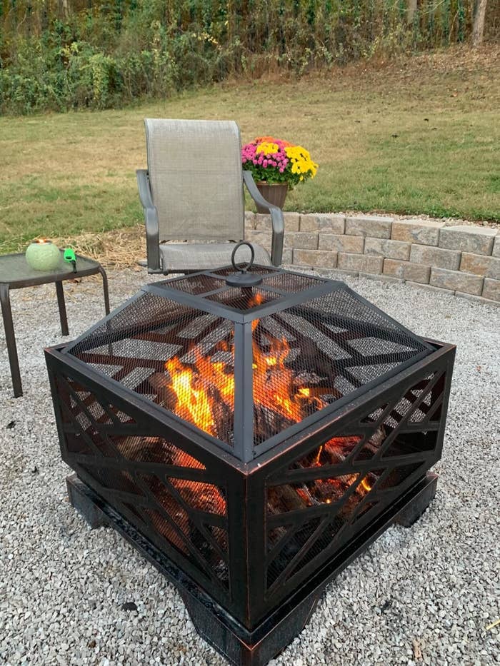 the firepit set on a large patch of gravel in a reviewer&#x27;s backyard