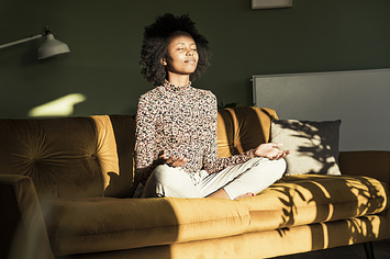 a woman meditates on a couch