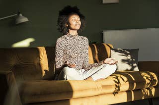 a woman meditates on a couch