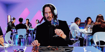 Keanu Reeves&#x27; character wearing headphones at a restaurant and crying into his glass of wine
