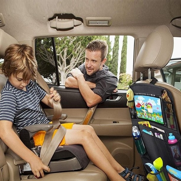 Kid sitting in car with dad in window and car organizer handing on seat