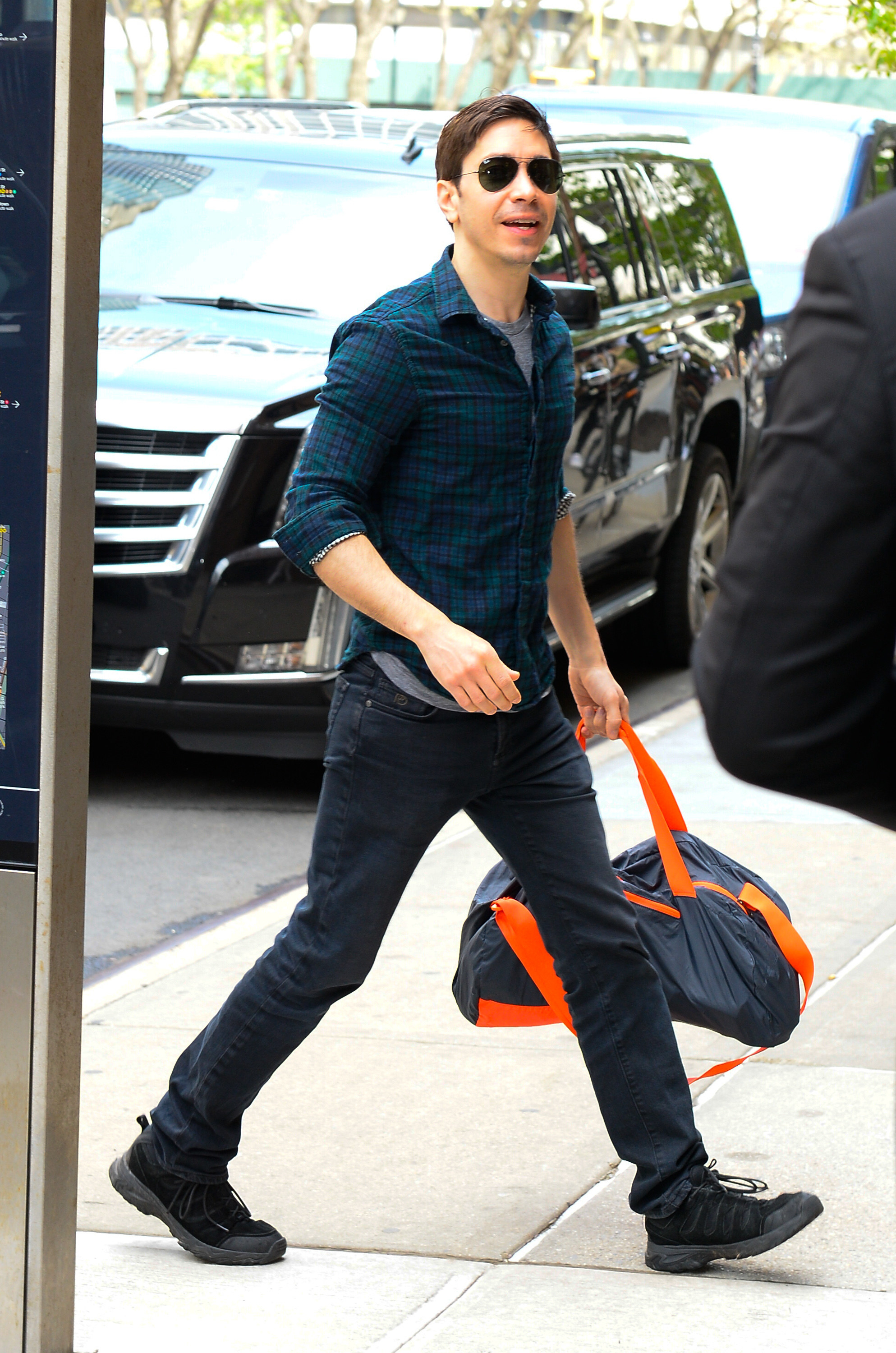 Justin walking down the street holding a duffel bag