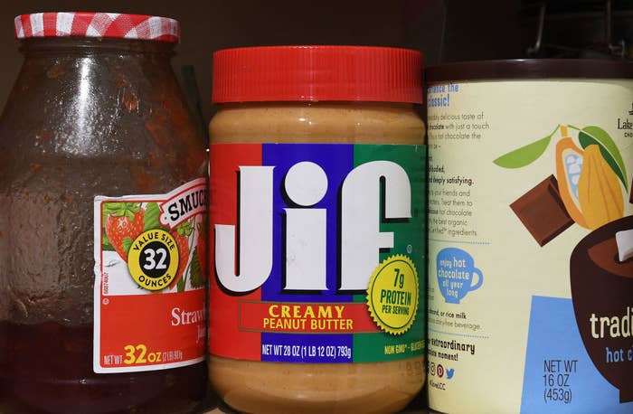 A jar of Jif creamy peanut butter alongside a jar of Smucker&#x27;s strawberry jam and a hot cocoa mix