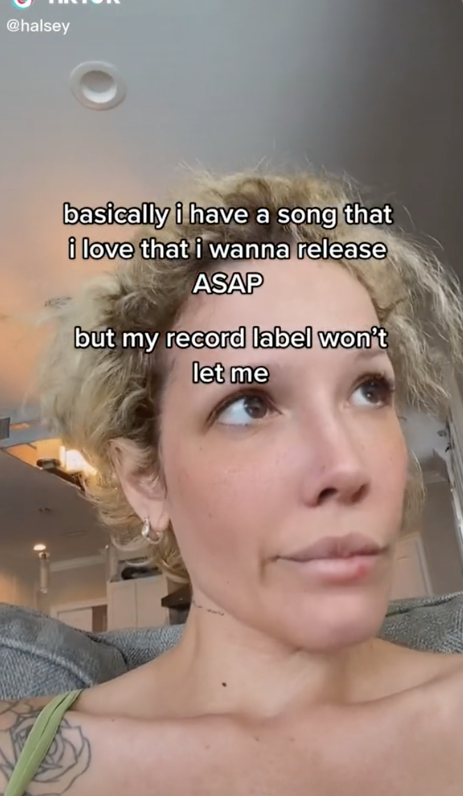 Closeup of Halsey on TikTok with text that says, &quot;basically i have a song that i love that i wanna release ASAP but my record label won&#x27;t let me&quot;