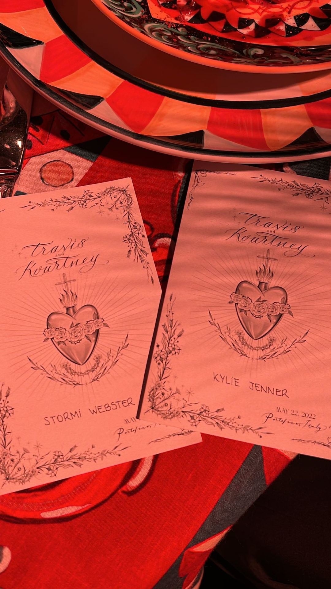 The place settings feature a flaming heart in the center, with Travis and Kourtney&#x27;s names above the heart and the guest&#x27;s name below it