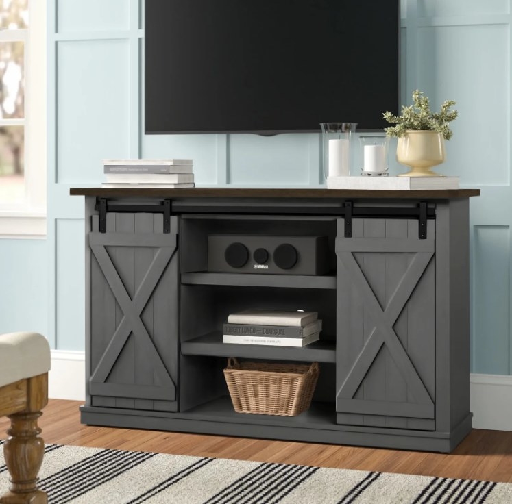 An image of a rustic TV stand with two sliding doors, two cabinets, and three open shelves