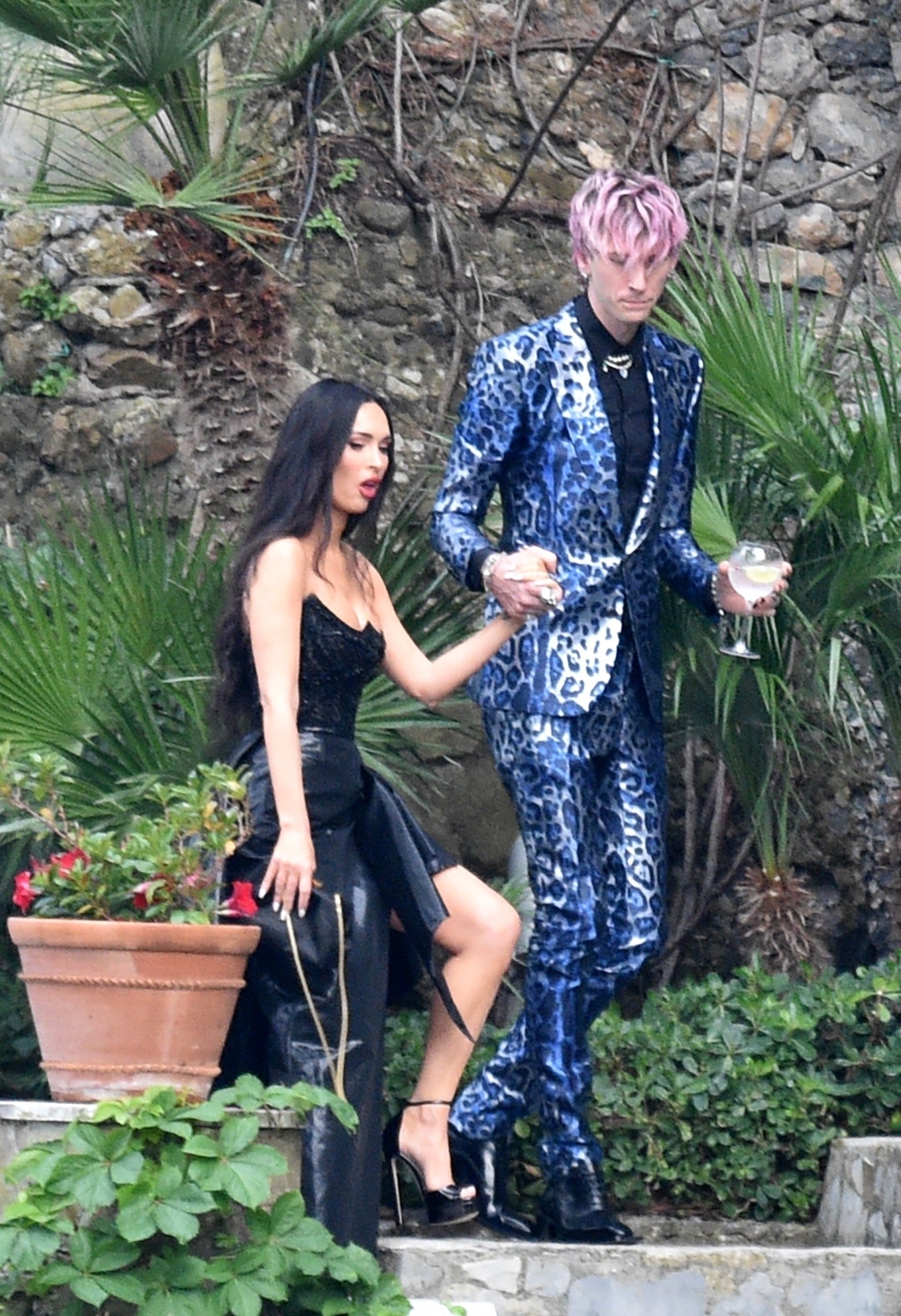 Megan and MGK walking into the wedding together; MGK is wearing a blue leopard print suit