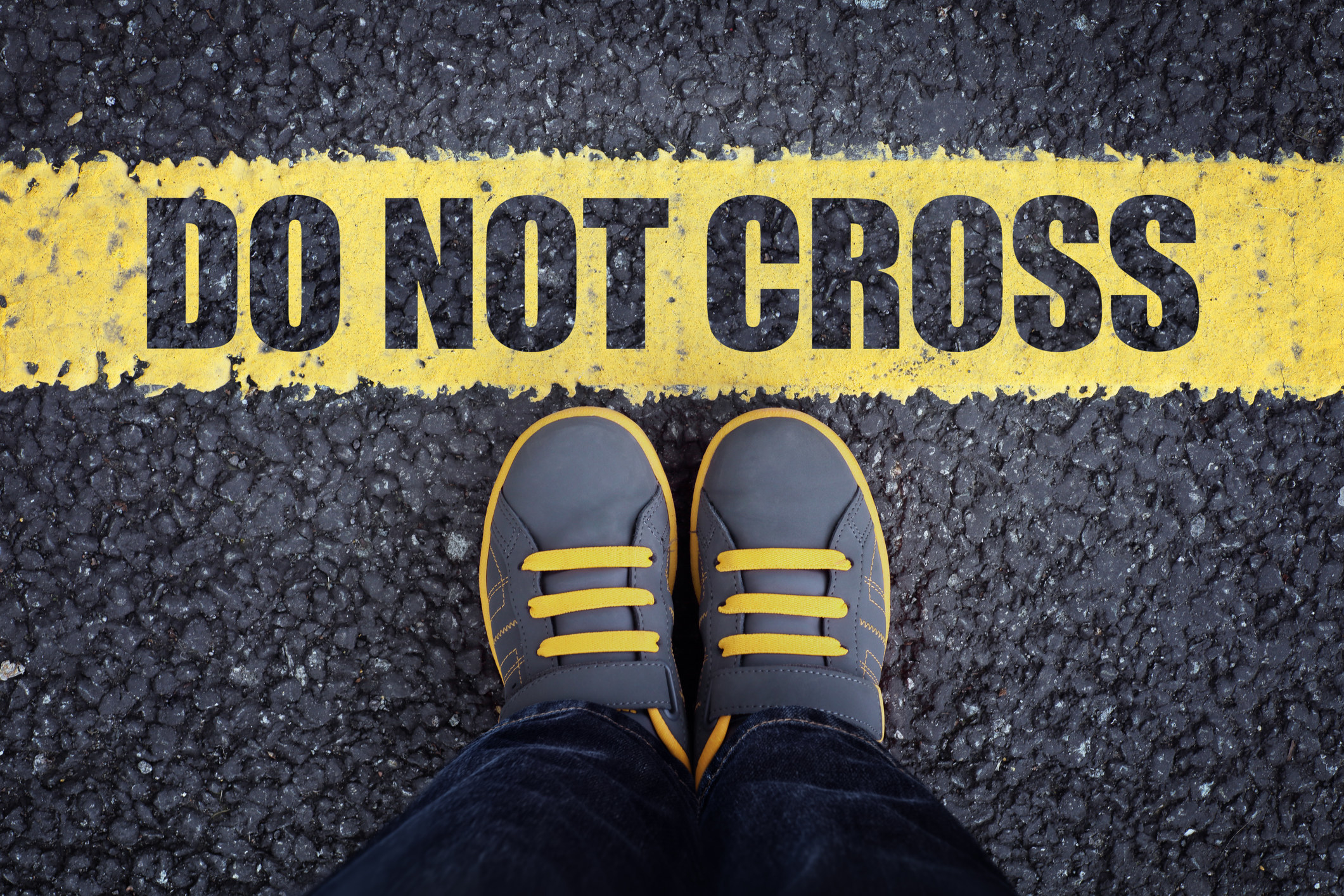 A person stands in front of a line that reads &quot;Do not cross&quot;