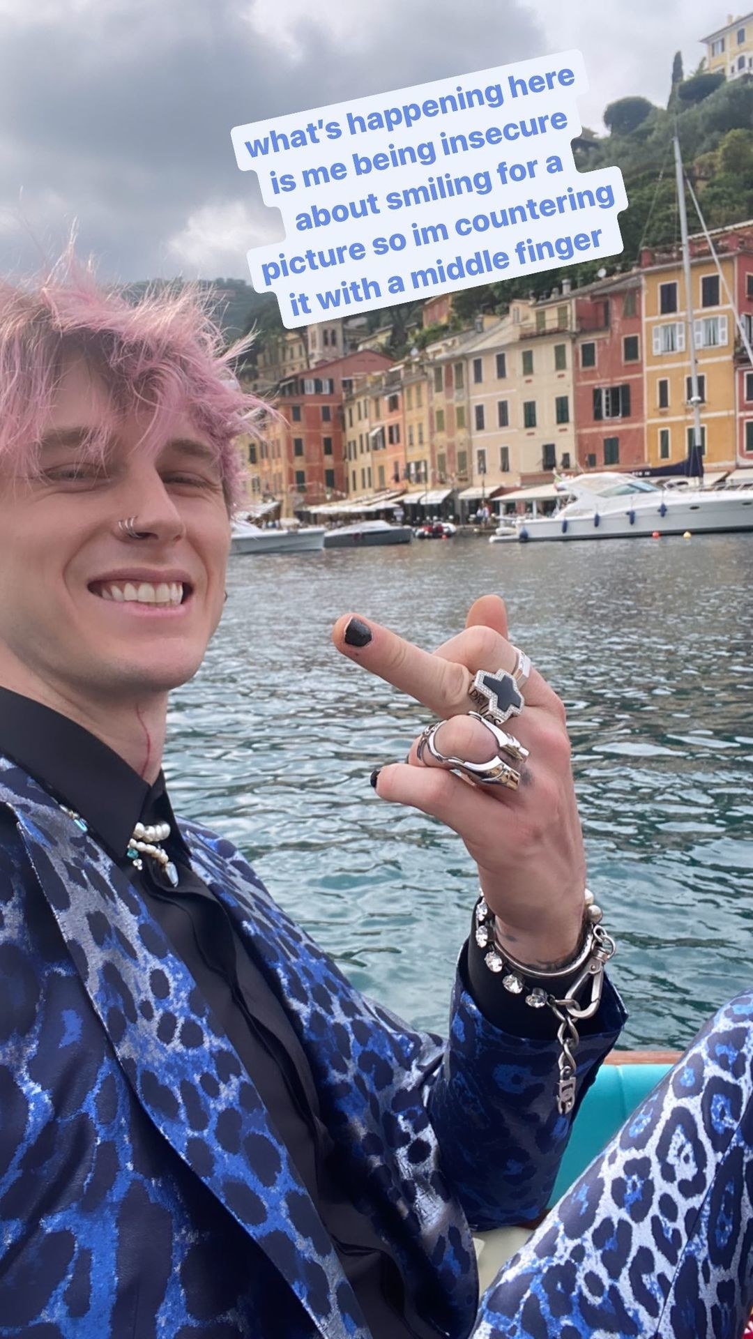 MGK smiling for a picture while holding up his middle finger, with a caption saying he&#x27;s doing it because he feels insecure