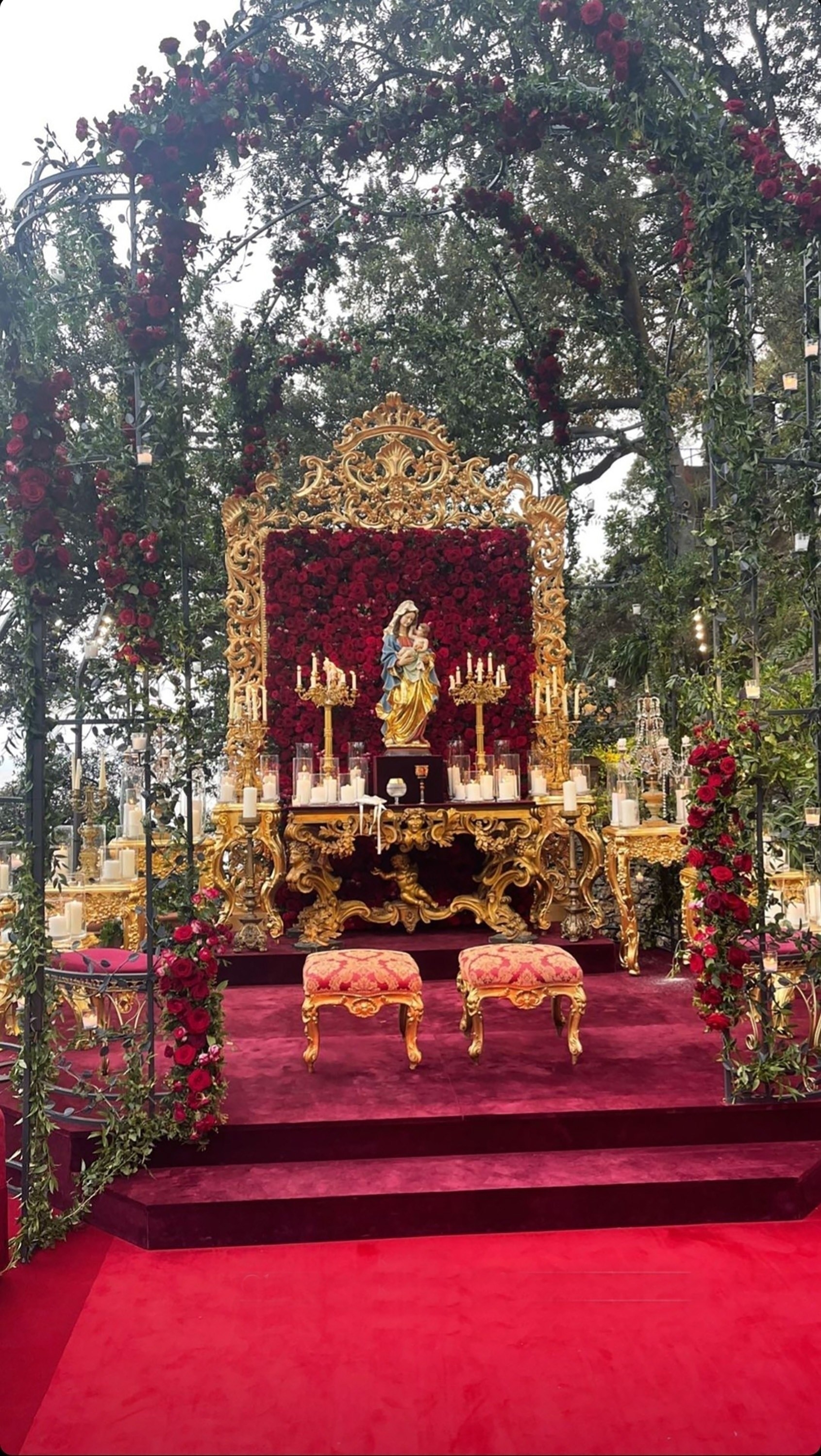 Stairs lead to an ornate alter with two footstools, a statue of a woman holding a baby, and countless numbers of candles