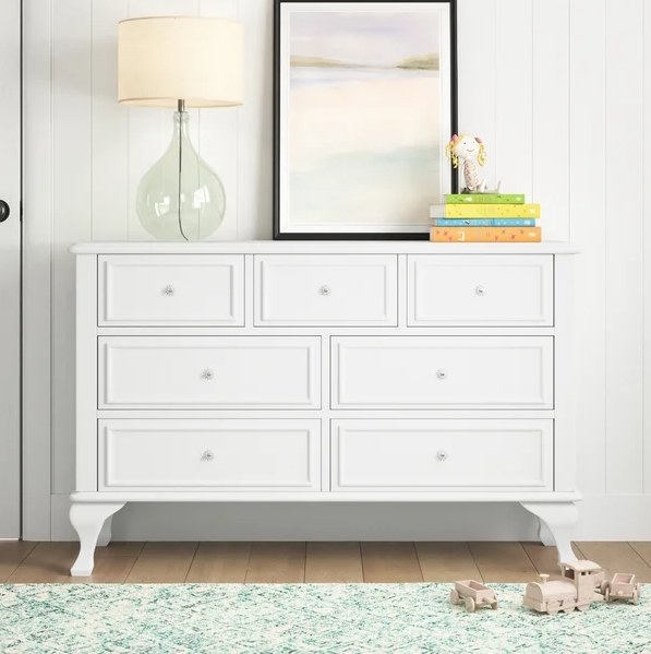 An image of a wide white seven-drawer dresser that comes with a tip-over restraint device