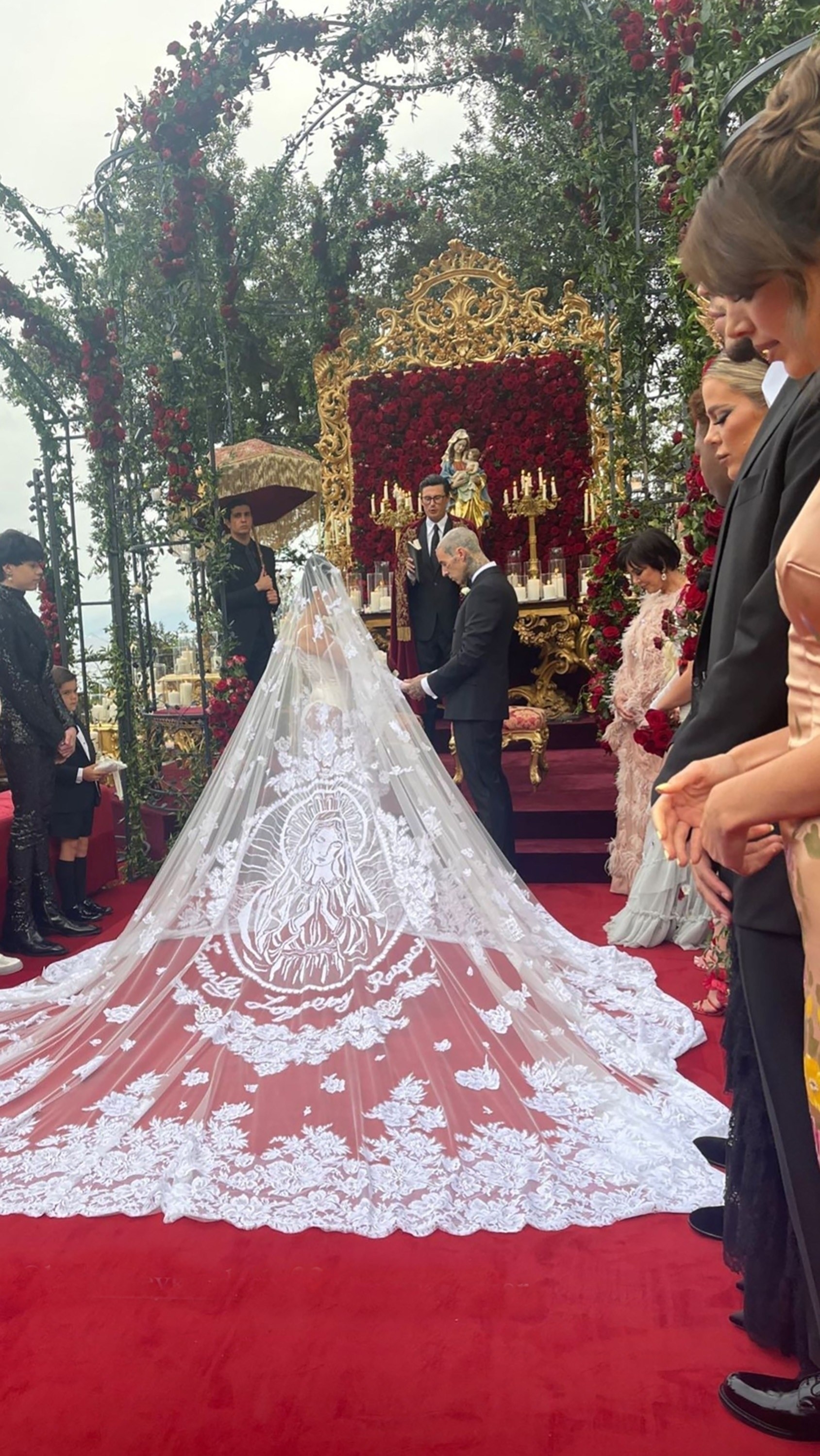 The back of Kourtney&#x27;s veil is huge, extending feet behind her, and it is embroidered with a woman praying