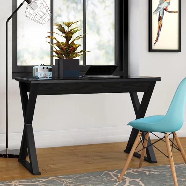 An image of a black glass desk with one center drawer and a powder-coated steel frame