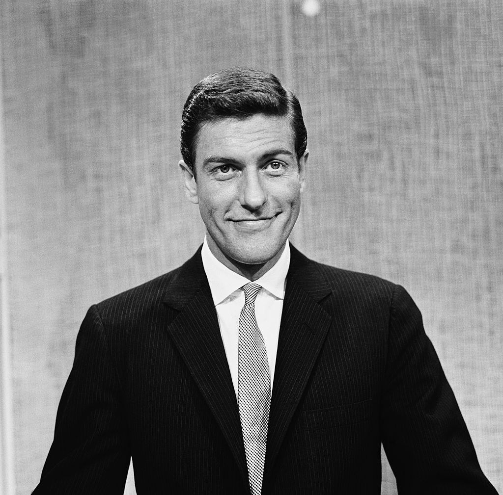 A young Dick Van Dyke with a full head of brown hair smiles at the camera