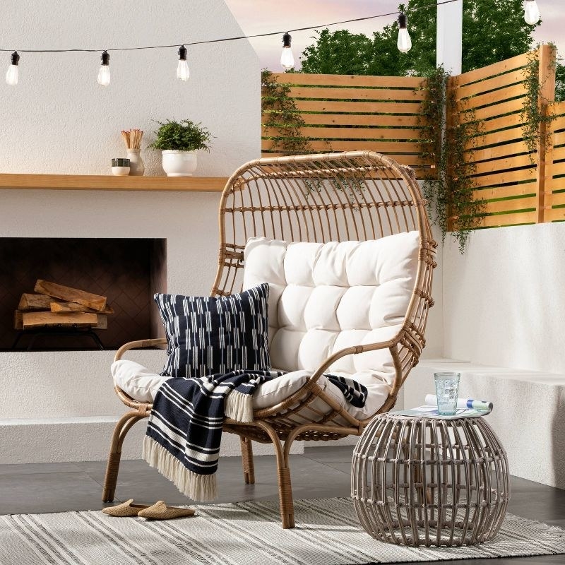 The wicker frame chair with white cushion and throw pillows on it