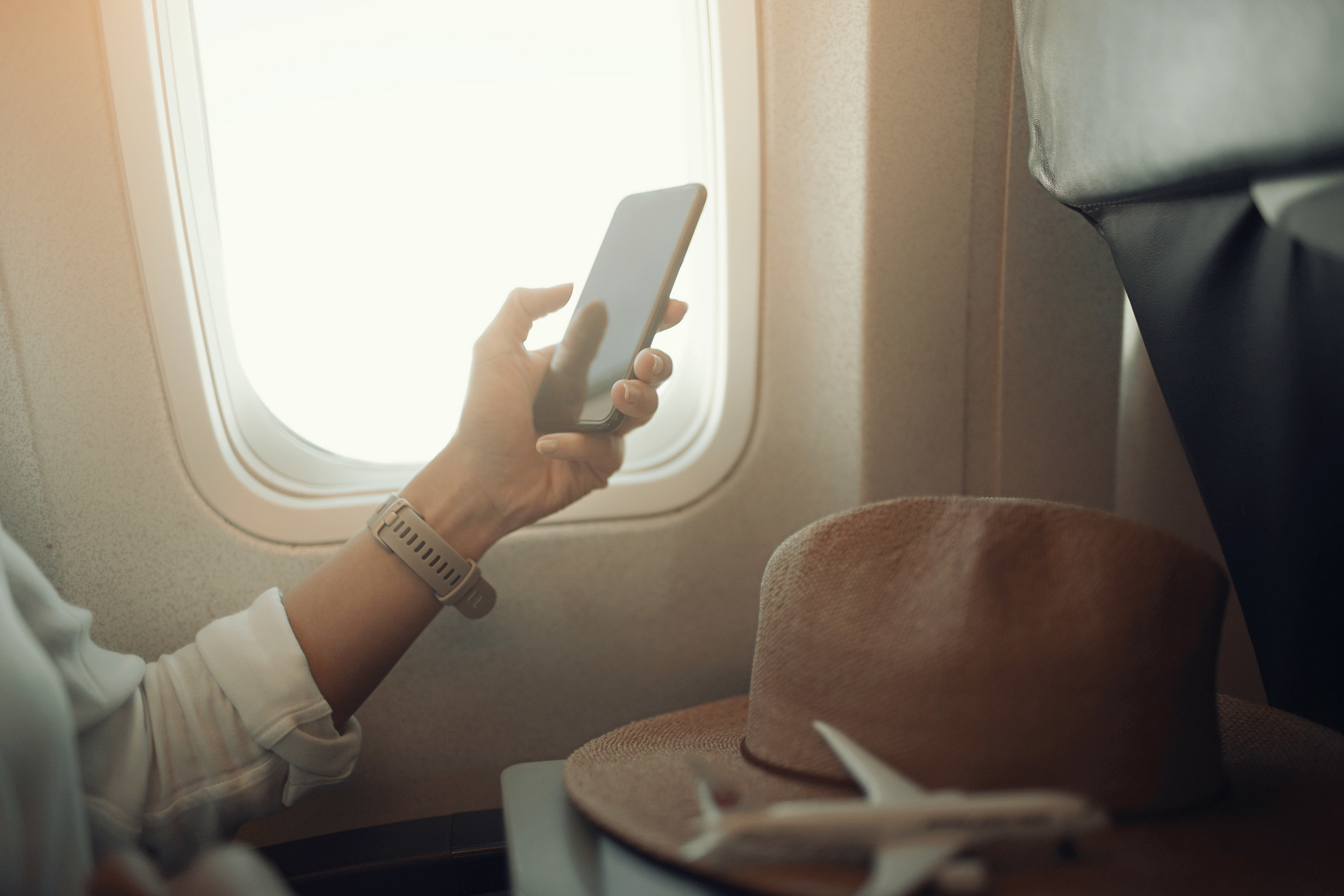 A plane passenger using a cell phone.