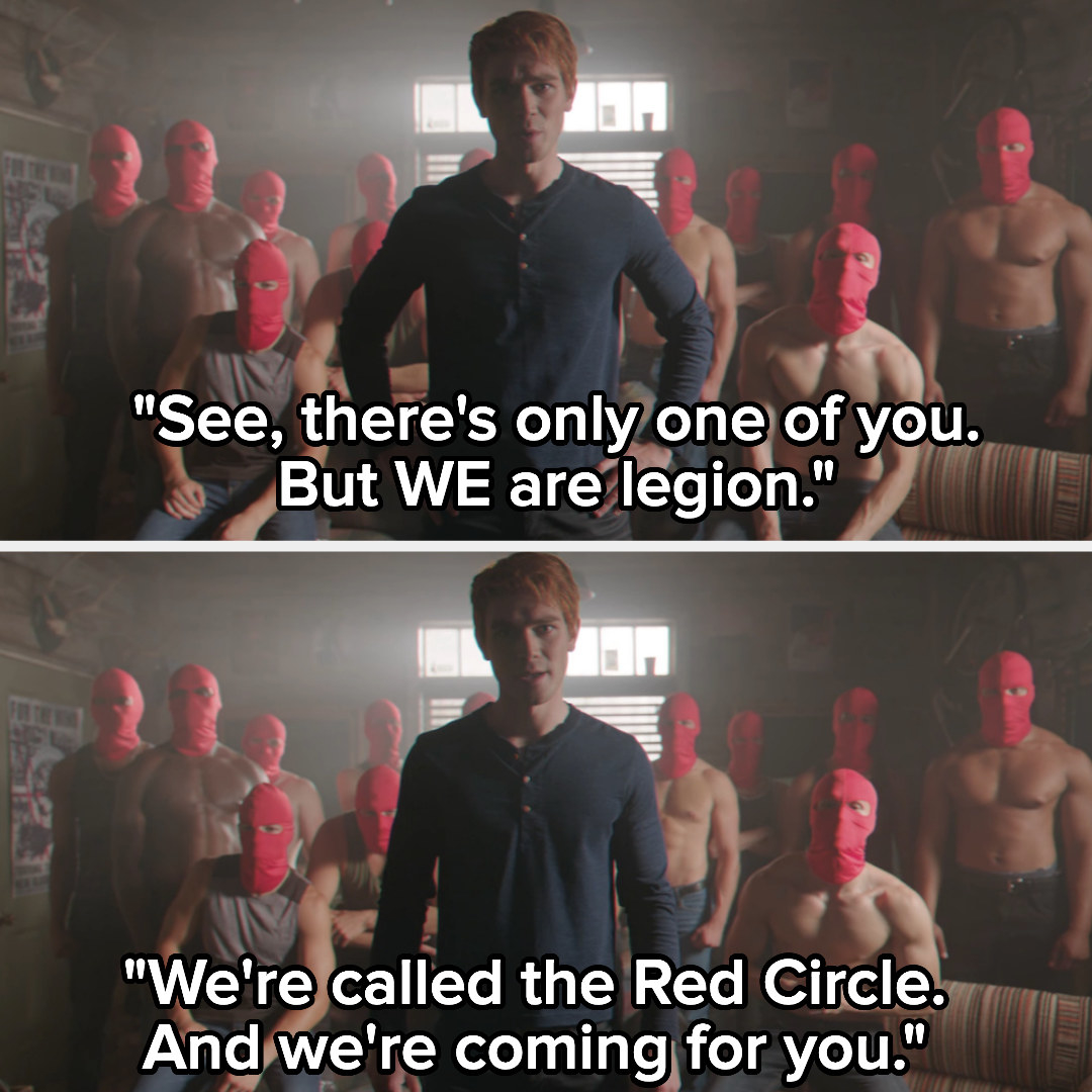 Archie standing with men with red hoods on