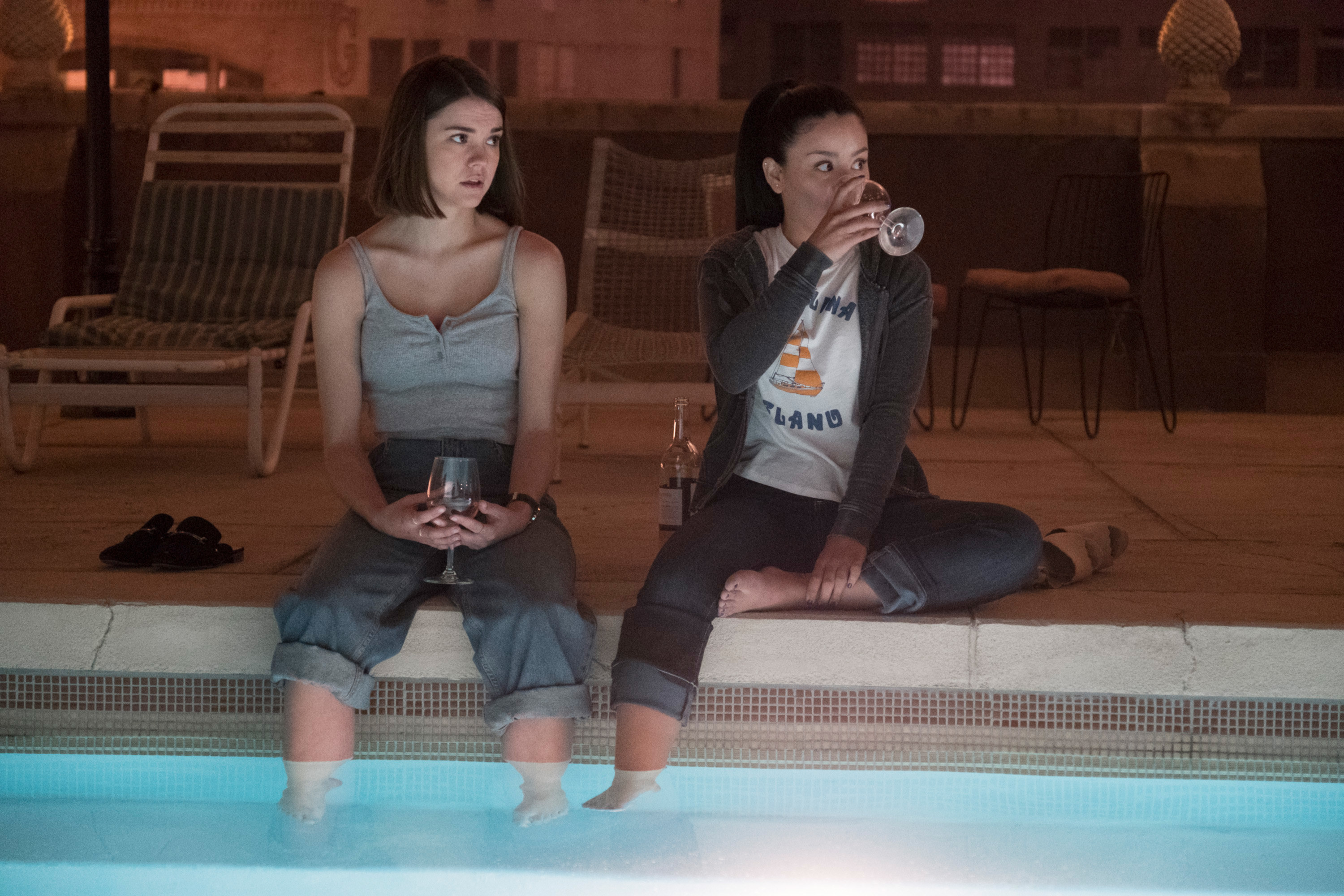 Callie and her sister drink wine with their feet in the pool