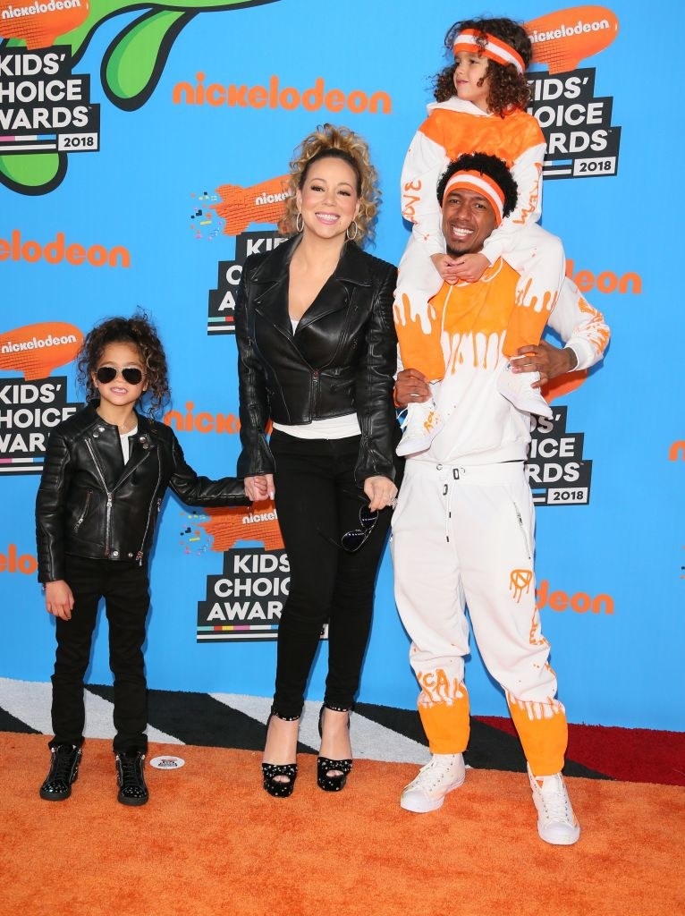 Monroe wears a dark suit, Mariah Carey wears a dark jump suit, and Nick and Morrocan wear matching sweatsuits