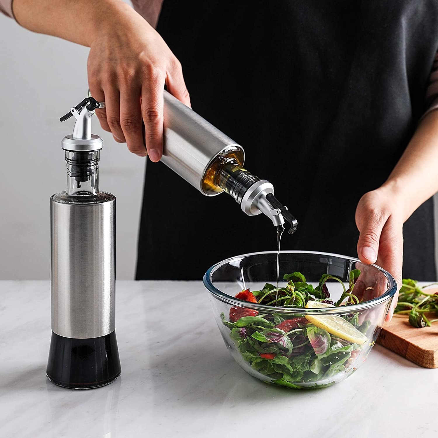 person dressing a salad with the oil and vinegar bottles