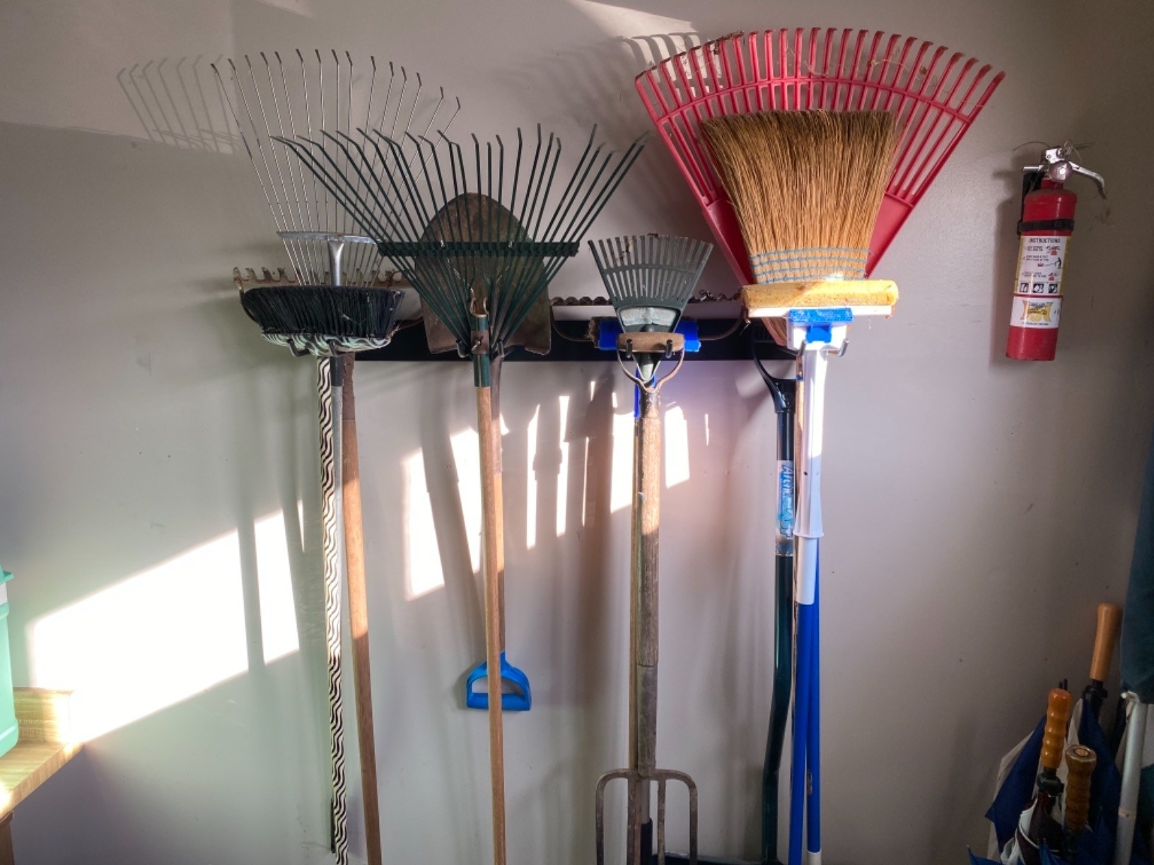 a reviewer&#x27;s tool rack on a wall, holding rakes and shovels