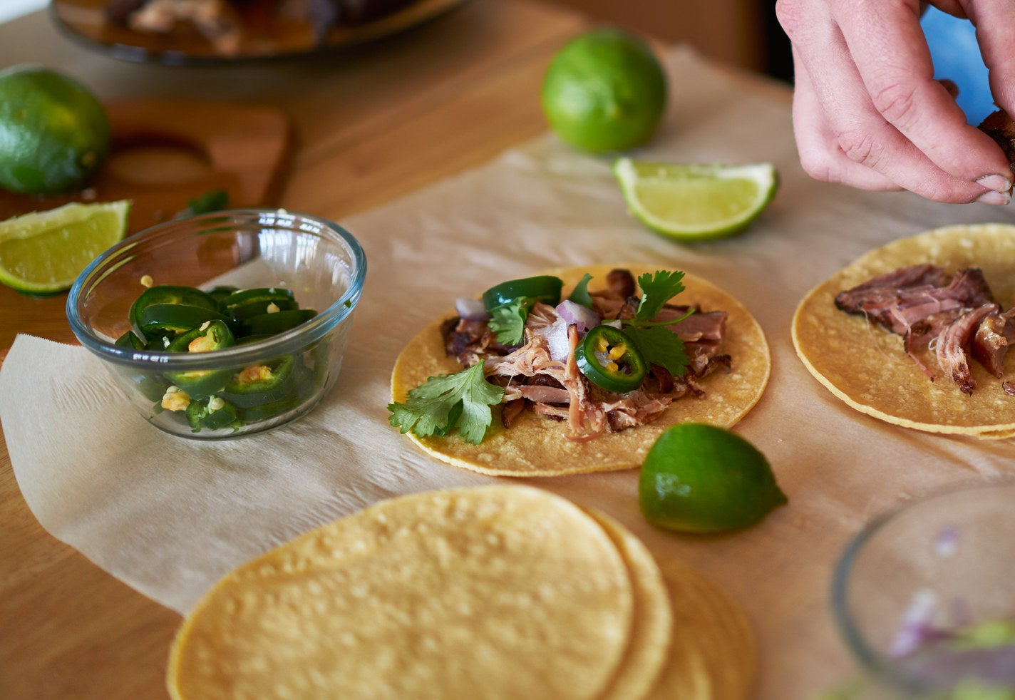 A person assembling meat tacos.