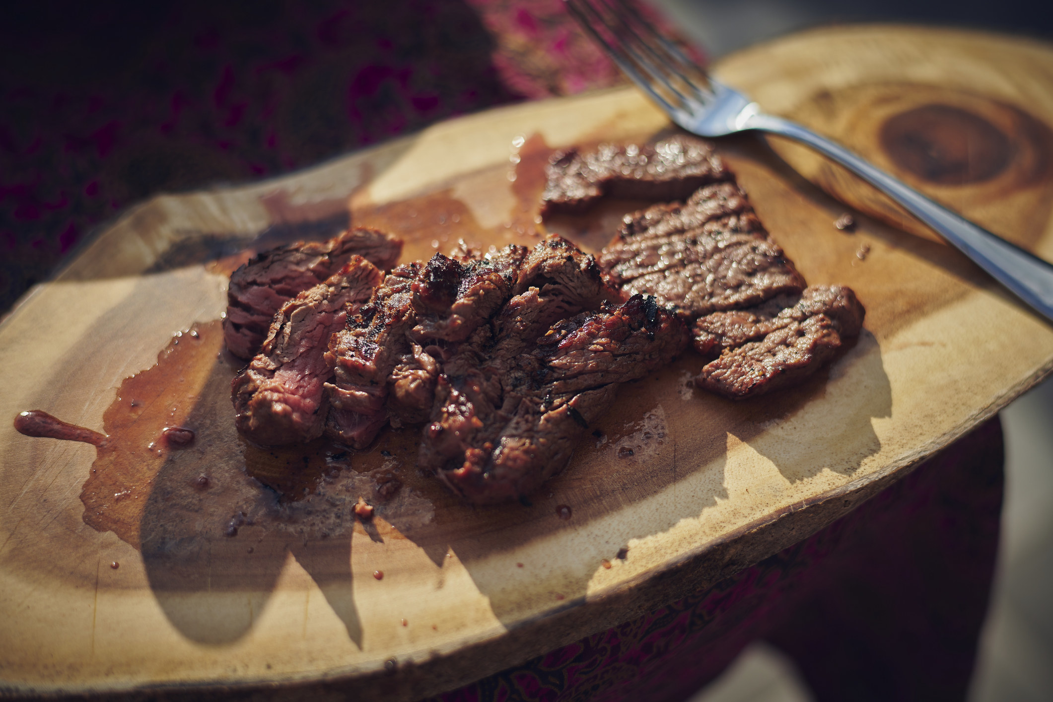 Close up of grilled tender steak in its juices on a cutting board.
