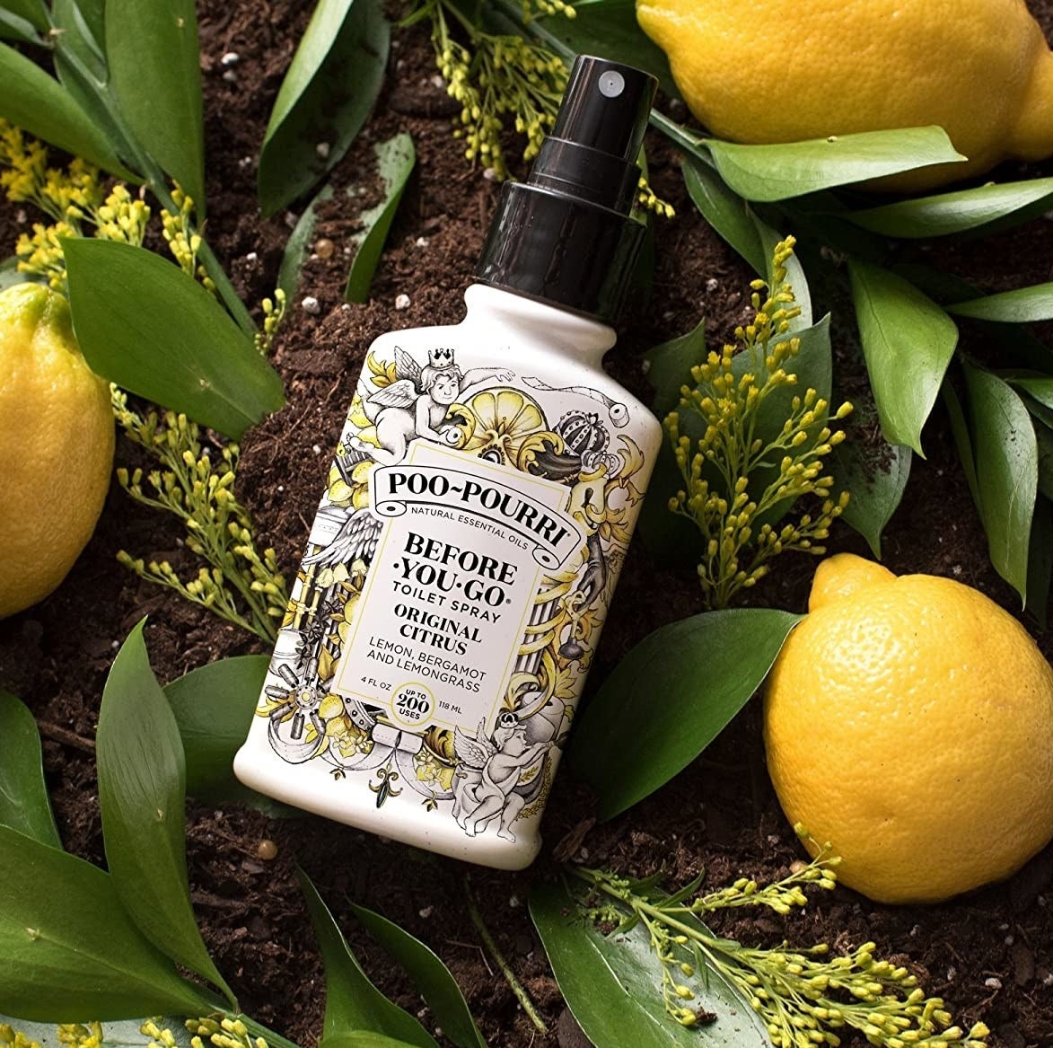 a bottle of poo-pourri toilet spray next to lemons and leaves