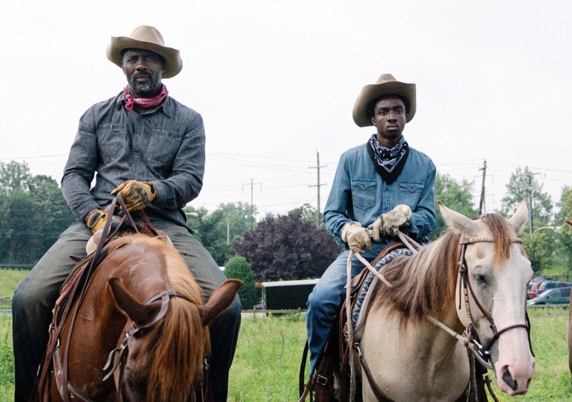 Caleb and Idris Elba on horseback in a scene from the movie