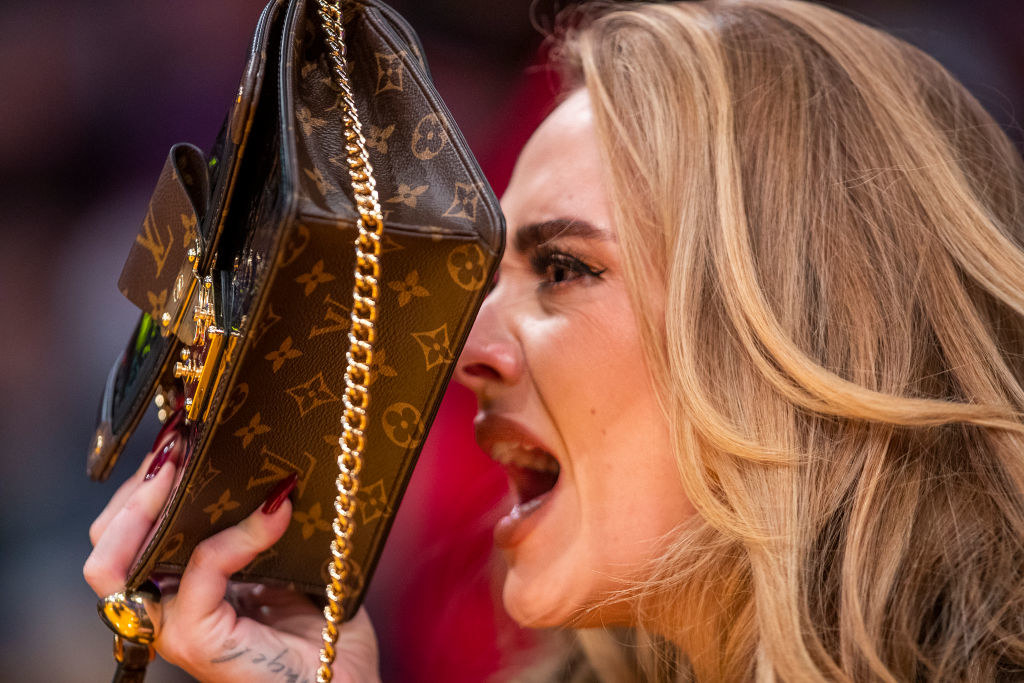 Adele yelling but holding up her handbag to block her face