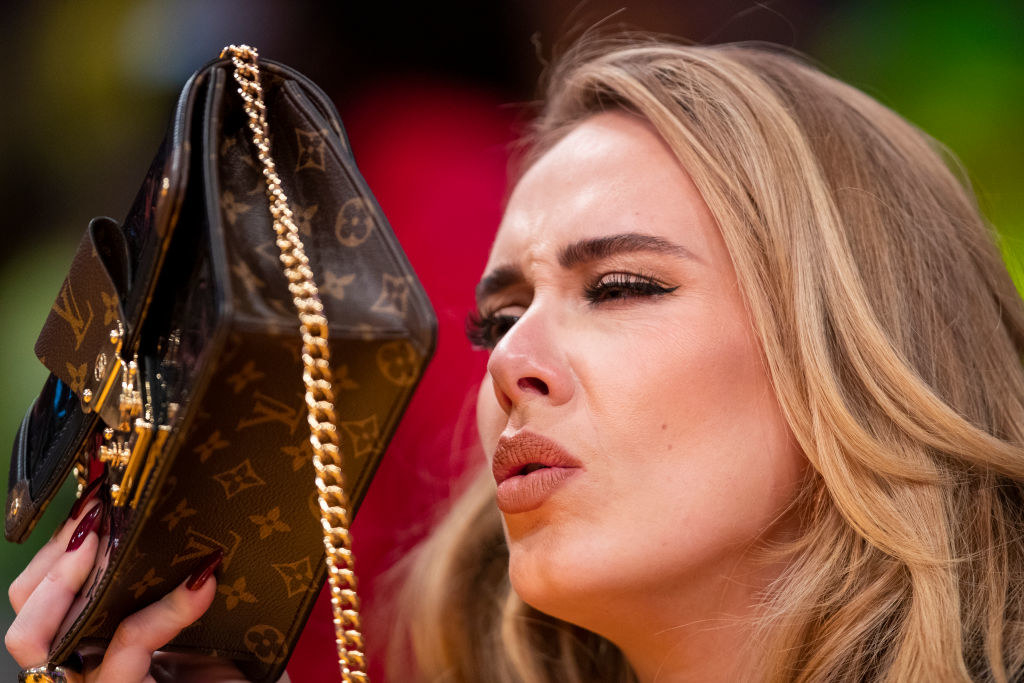 Adele holding up a Louis Vuitton purse over her face