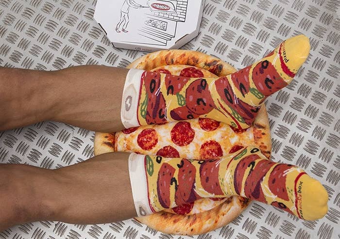 A person wearing a pair of pizza socks on top of a pizza cushion
