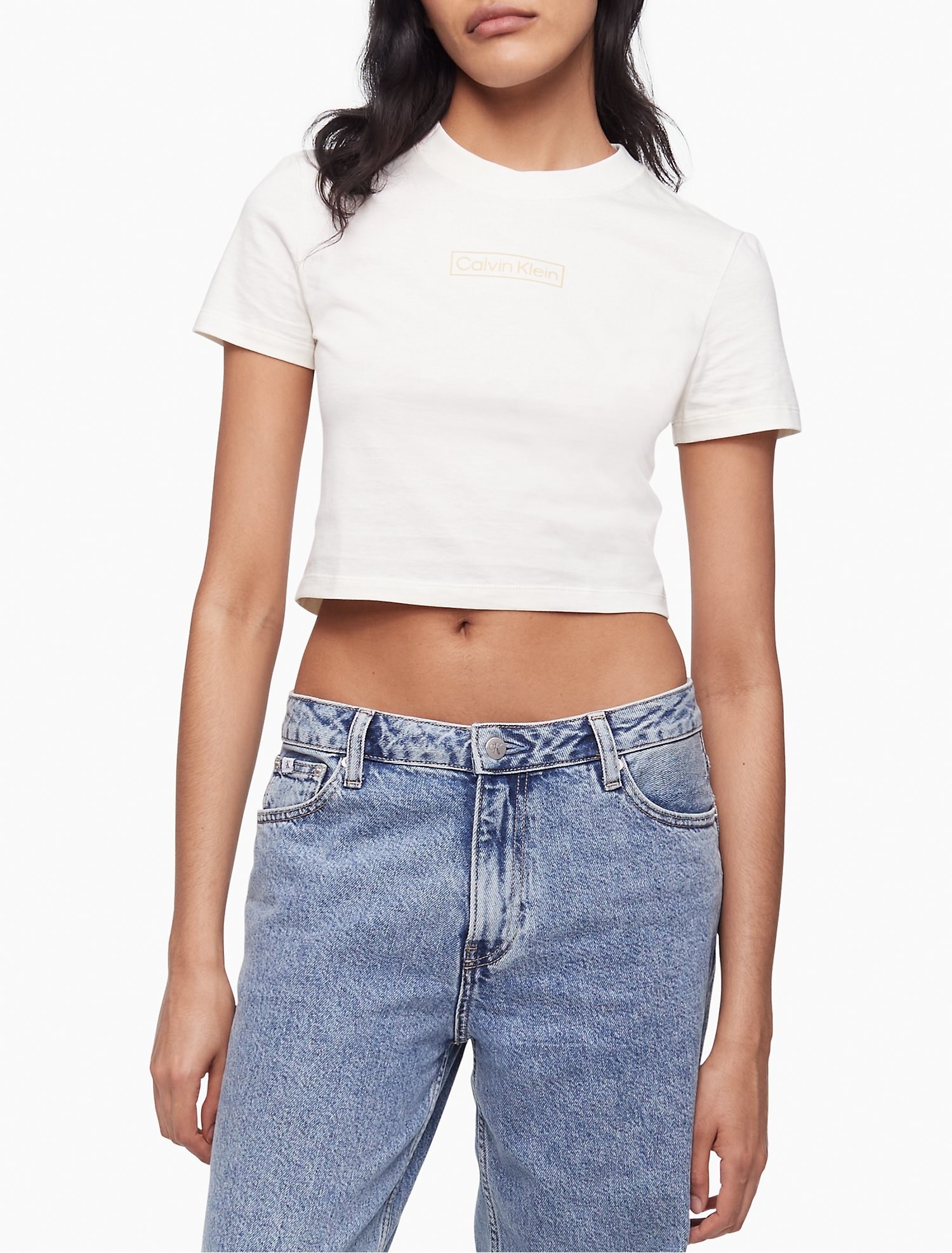 Model wearing white crop top and low rise medium wash jeans